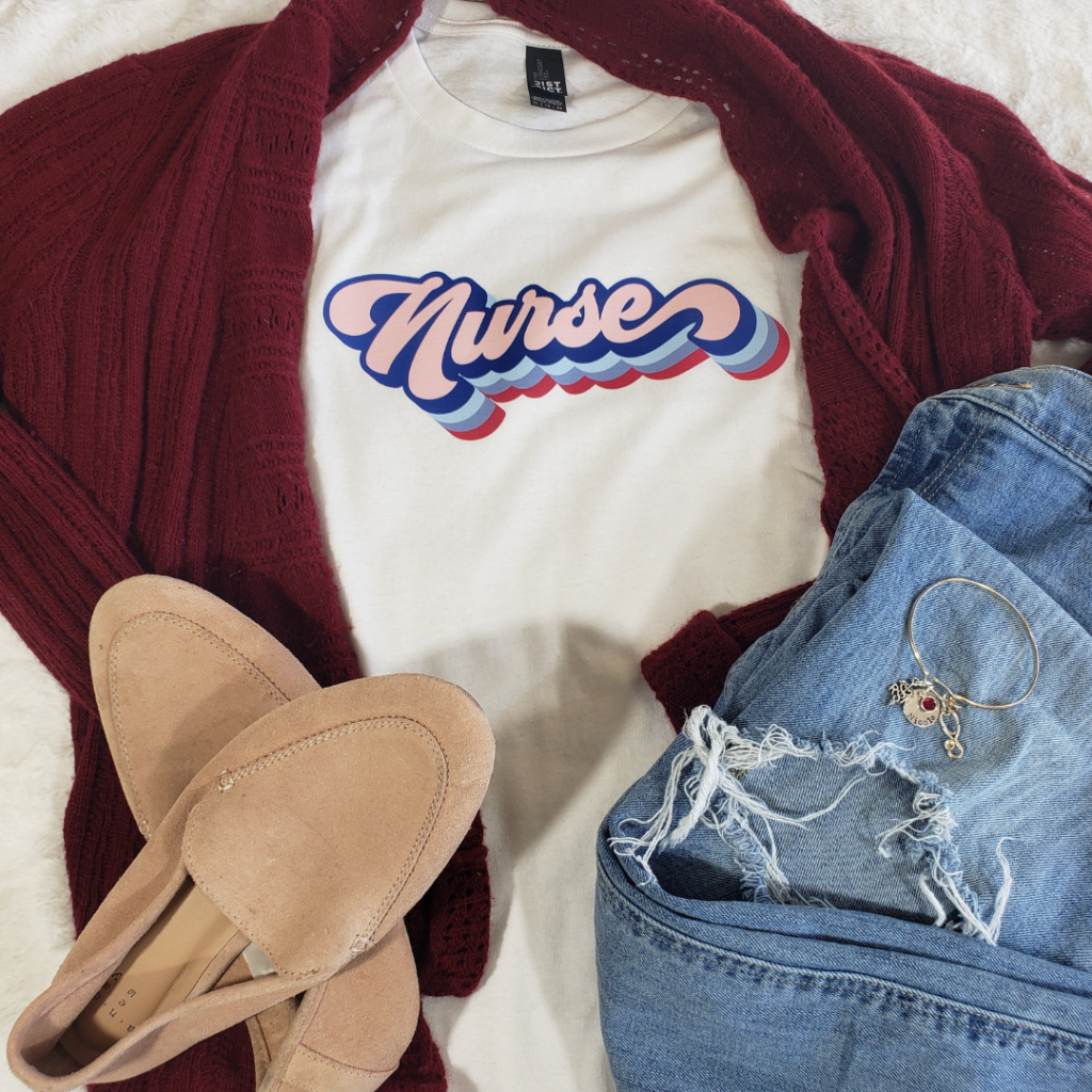 Red cardigan sweater with white tshirt that says Nurse on it in retro font with pink flats and jeans and bangle bracelet