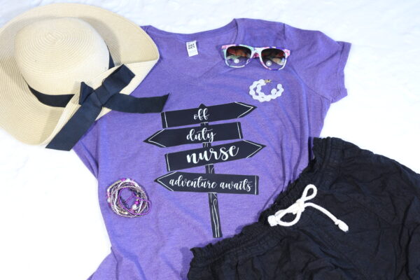 Purple vneck tshirt that says Off Duty Nurse Adventure Awaits on sign posts, black shorts, tan hat with black bow, sunglasses, white earrings, and stacking bracelets