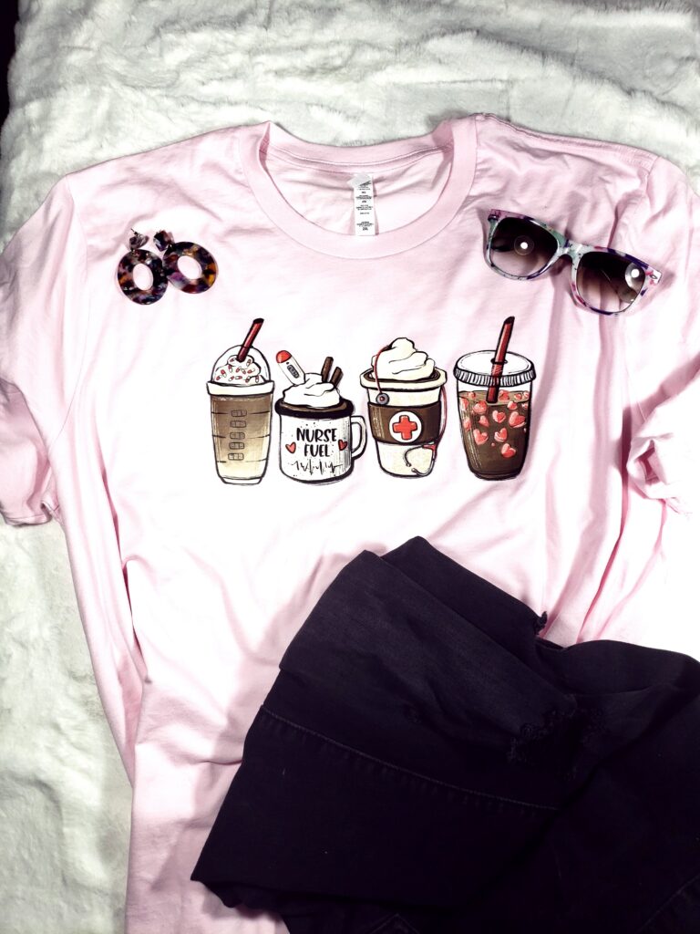 Nurse pale pink tee with coffee cups, black ripped jeans, sunglasses and earrings